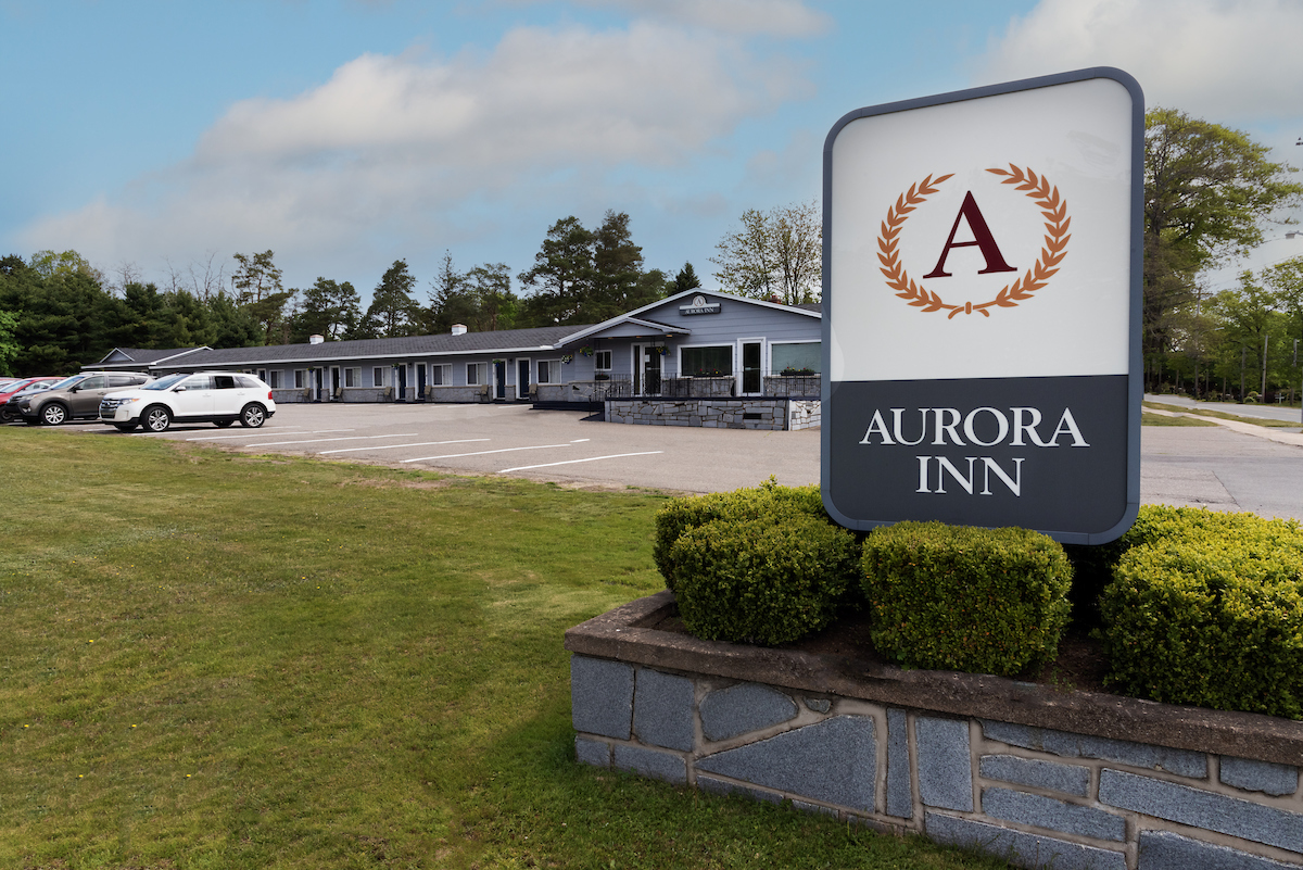 Entrance sign of Aurora Inn with a view of the welcoming motel facade and parking area in Annapolis Valley.