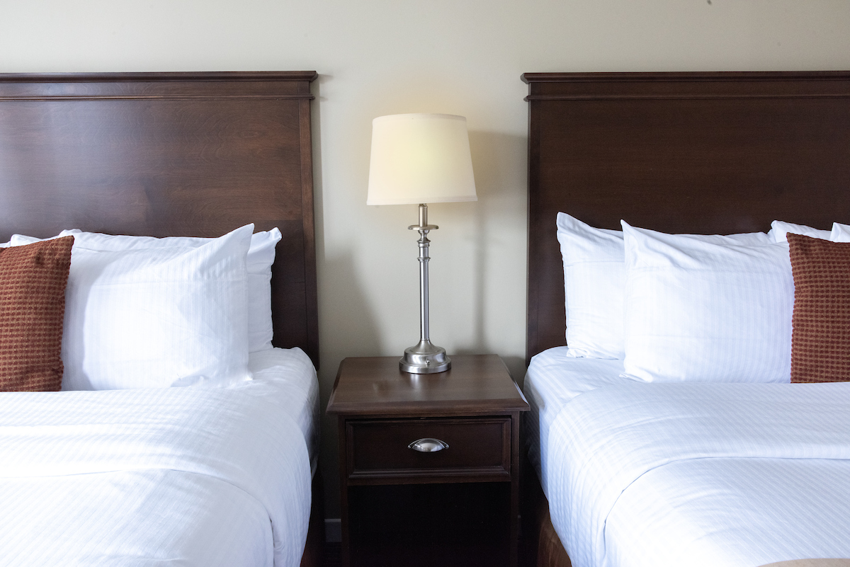 Two comfortable single beds in an Annapolis Valley Motel room, with clean white linens and elegant wooden headboards