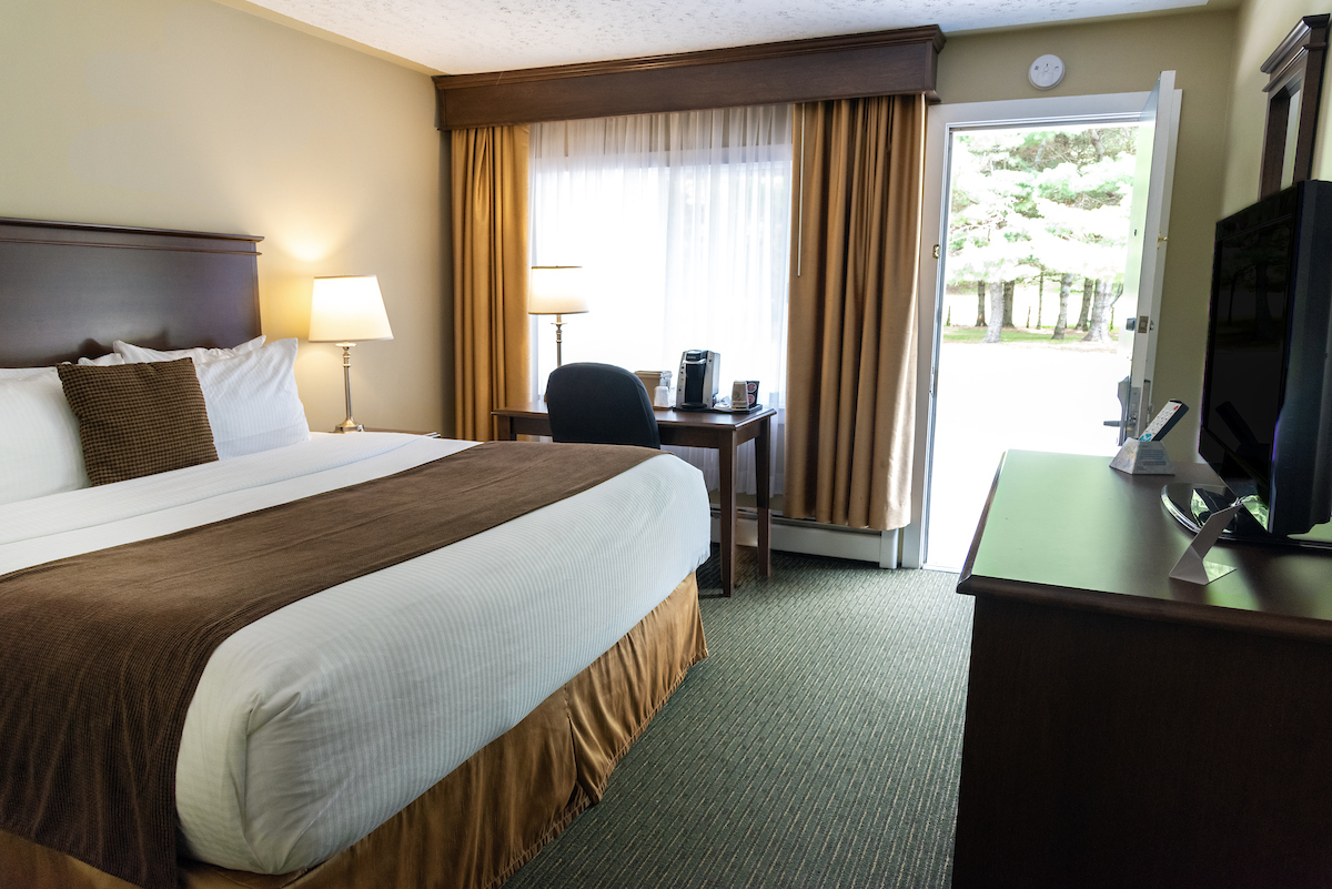 Elegant Annapolis Valley motel room featuring a king-sized bed, a well-appointed work area, and a view to the outdoors.