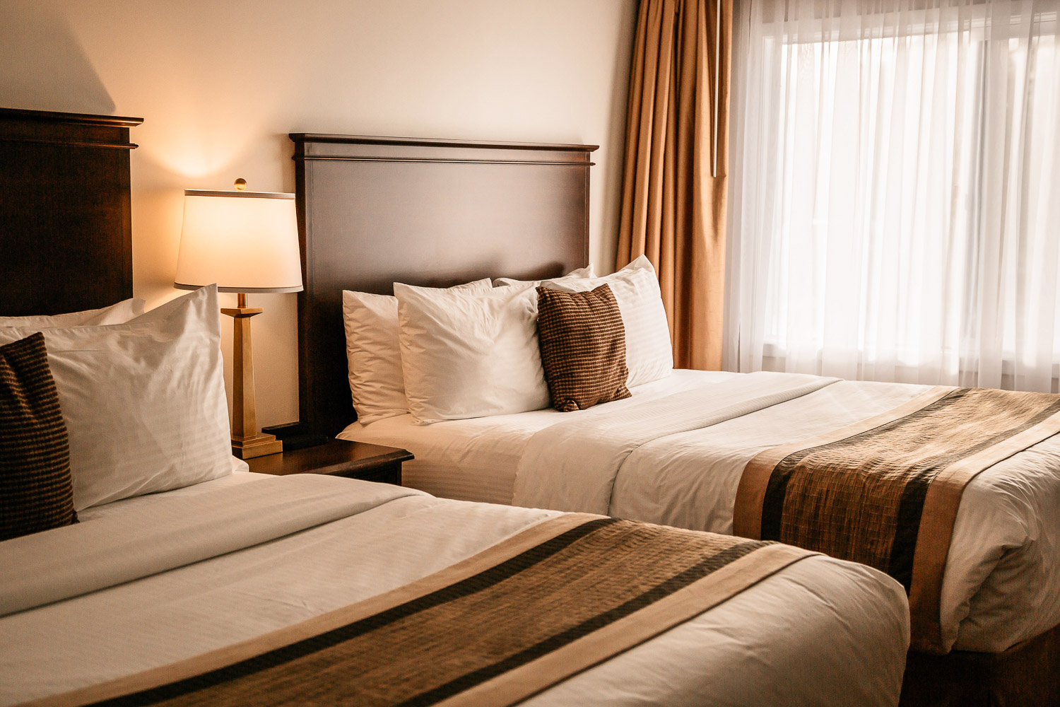 The sun shines through the window into the Queen Room with two queen beds