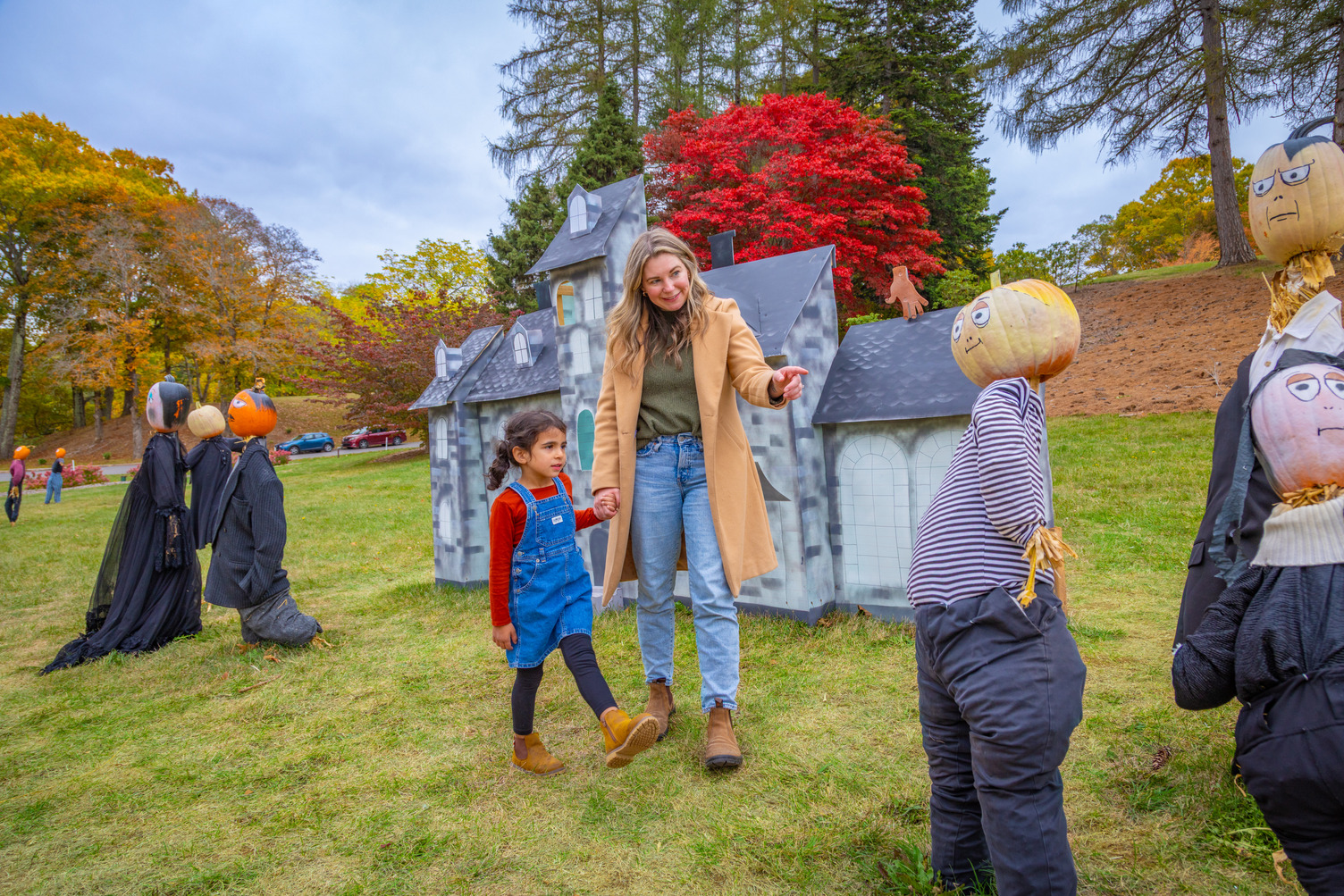 A mother and child walk through a display of people with pumpkins for heads in Kentville, Nova Scotia.